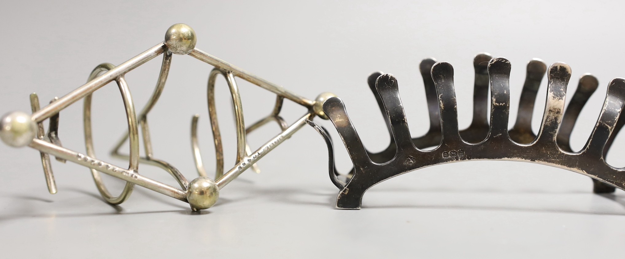 A George VI silver demi-lune six division toast rack by Adie Brothers, Birmingham, 1949, 13.8cm, together with a novelty metal toast rack by Hukin and Heath, the divisions spelling the word 'Toast'.